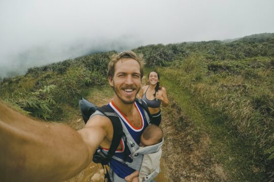 woman, man and baby taking photo surrounded grass