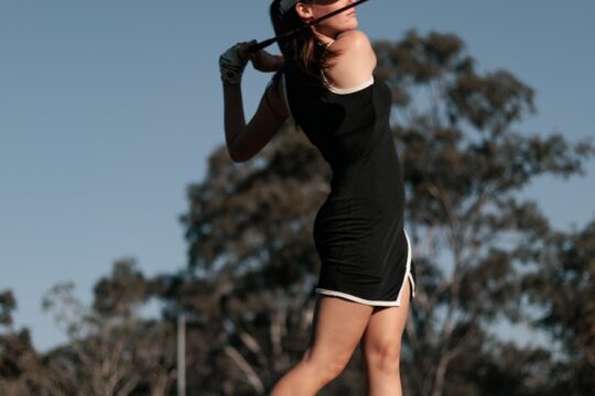 a woman swinging a golf club at a ball