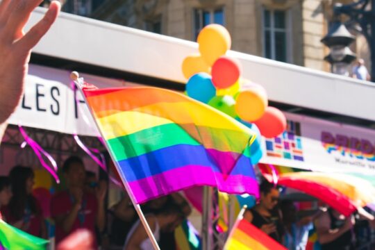 people holding yellow, green, blue, and purple flag