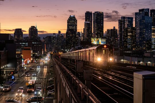 cars on road between high rise buildings during night time