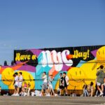 a group of people walking in front of a colorful wall