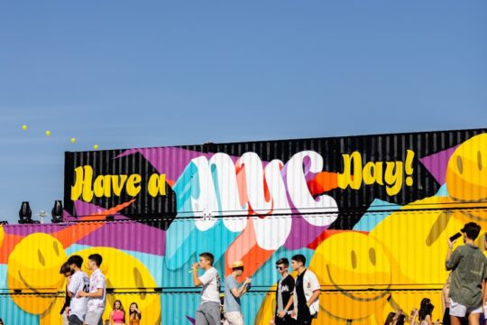 a group of people walking in front of a colorful wall